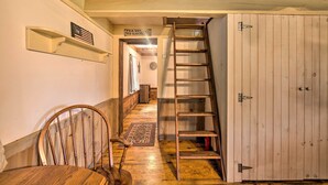 A wooden staircase leading to a lofted area with a chair and a small table. A 'No Smoking' sign is visible on the wall. - Remote 1901 Studio Cabin w/ Loft - Pets Allowed! (Allenwood)