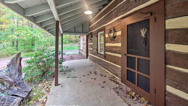 A covered porch with a concrete floor, wooden beams, and a brick wall. - Remote 1901 Studio Cabin w/ Loft - Pets Allowed! (Allenwood)