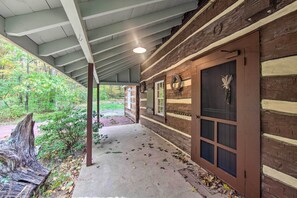 A covered porch with a concrete floor, wooden beams, and a brick wall.