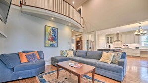 A spacious living room with a curved staircase, a large sectional sofa, and a wooden coffee table. - 2 Mi to Dtwn: Home in Noda District Near Unc! (Charlotte)