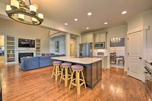 A modern kitchen with a central island, bar stools, a dining area, and a living room with a sofa and TV. - 2 Mi to Dtwn: Home in Noda District Near Unc! (Charlotte)