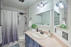 A modern bathroom with a shower, toilet, sink, and large mirror. - Sunny Brandon Getaway w/ Fire Pit! (Brandon)