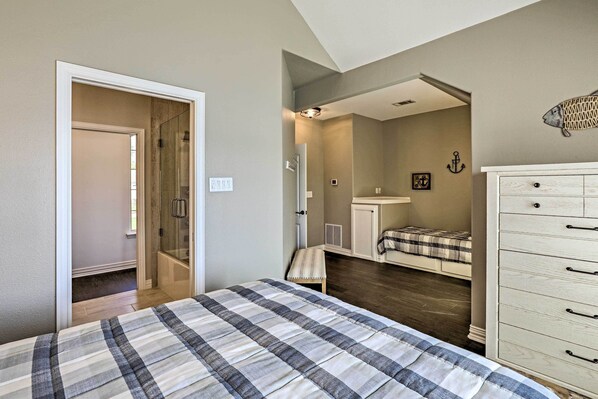 A bedroom with a bed, a dresser, a closet, and a bathroom with a shower and toilet. - Lavish Lake House, Near Vineyards + Marinas! (Granbury)