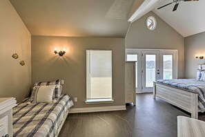 Une chambre avec deux lits, une fenêtre avec des stores, un ventilateur de plafond et une porte donnant sur un balcon.
