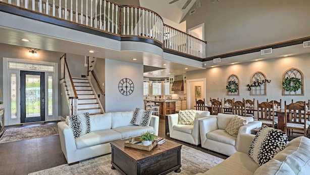 A spacious living room with a high ceiling, a staircase, and a dining area. - Lavish Lake House, Near Vineyards + Marinas! (Granbury)