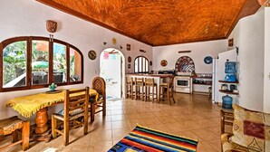 A spacious living area with a wooden ceiling, a dining table with chairs, a colorful rug, and a kitchen in the background. - Tropical Sayulita Condo w/ Patio & Beach Access! (Sayulita)