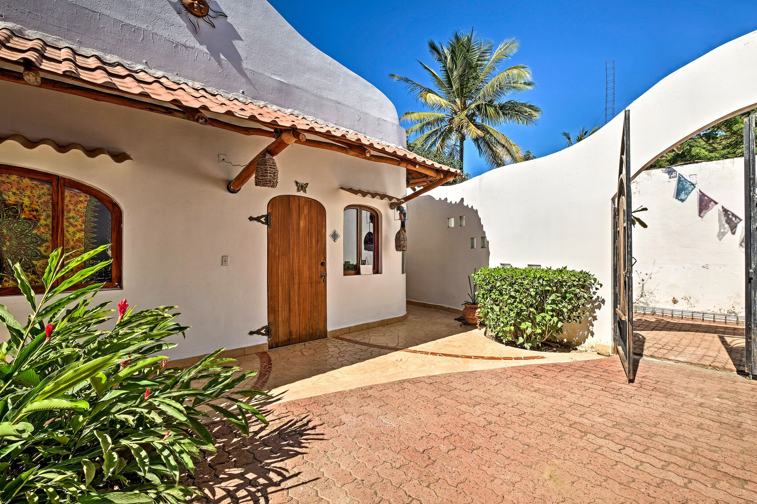A white building with a tiled roof, a wooden door, and a small window.