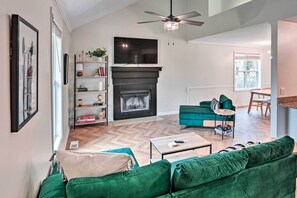 A living room with a fireplace, green sofa, and a flat-screen TV mounted above it.