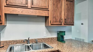 A kitchen with wooden cabinets, a granite countertop, a double sink, and a coffee maker. - Updated Hendersonville Home ~ 3 Mi to Lake! (Hendersonville)