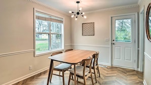 A dining area with a wooden table and chairs, a window with blinds, a door with a view, and a ceiling light fixture. - Updated Hendersonville Home ~ 3 Mi to Lake! (Hendersonville)