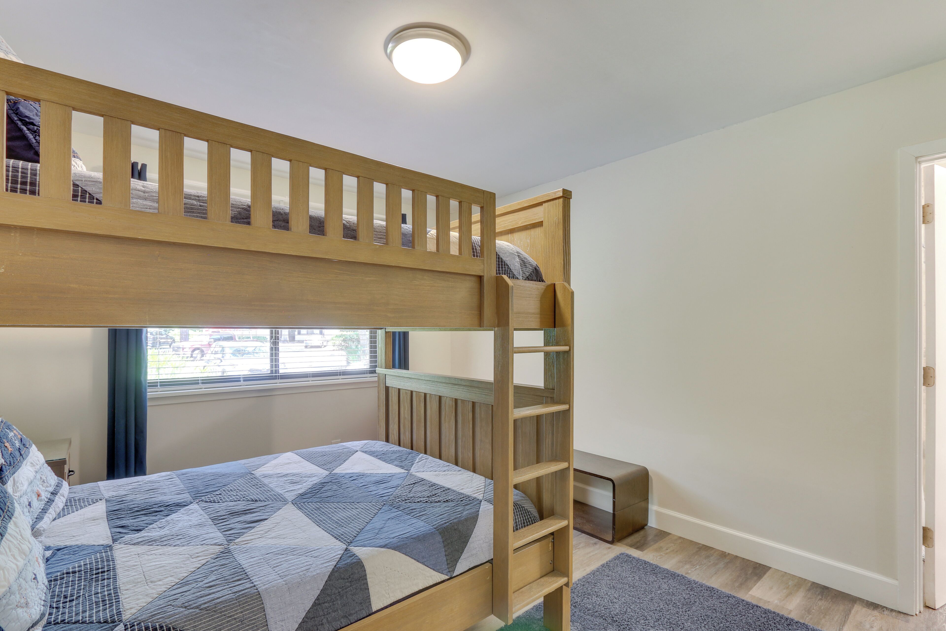 A bunk bed room with a window, a desk, and a door.