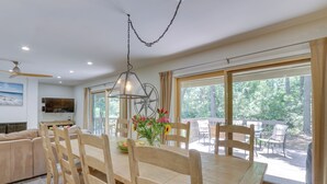 A dining area with a wooden table and chairs, a hanging light fixture, and large windows offering a view of the outdoors. - 1 Mi to Harbour Town: Sea Pines Resort Home (Hilton Head Island)