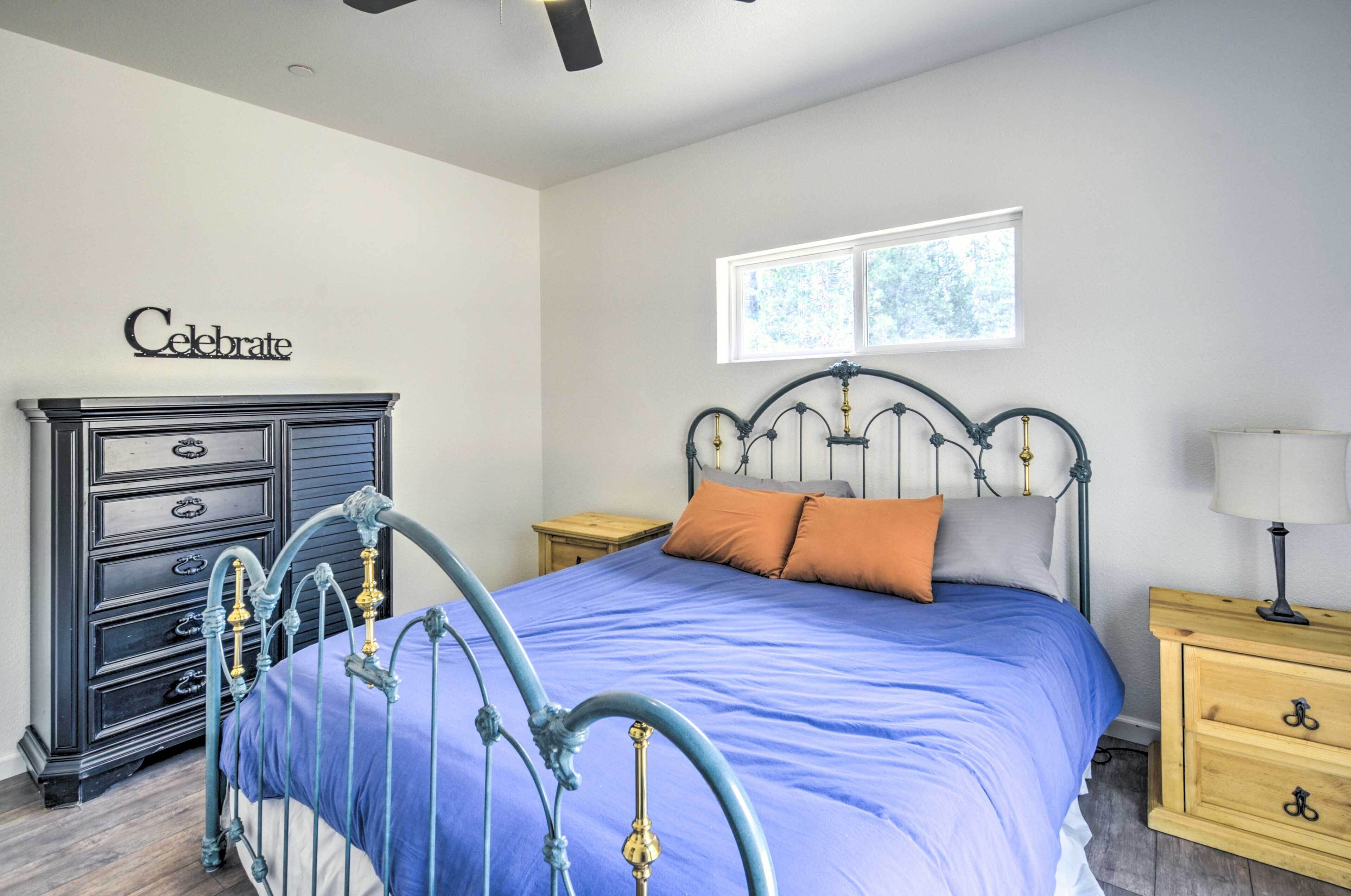 A bedroom with a bed, dresser, nightstand, and a window.