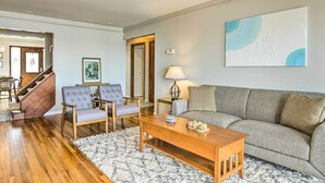 A living room with a wooden floor, a grey sofa, a wooden coffee table, and a grey armchair. - Anchor Bay Getaway on Lake St Clair With Dock! (New Baltimore)