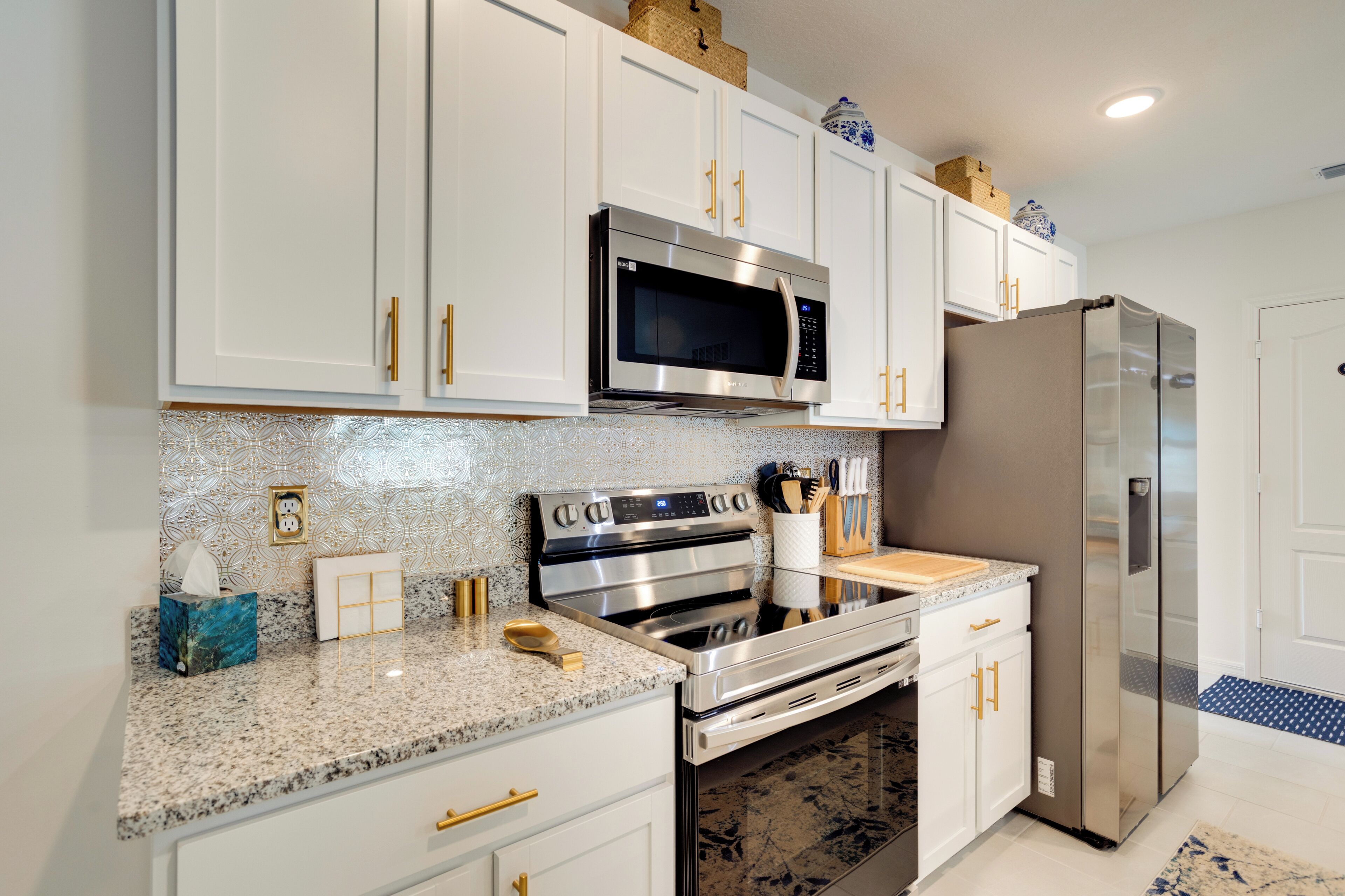 A modern kitchen with white cabinets, stainless steel appliances, and granite countertops.