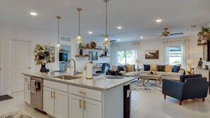 A spacious living area with a large island, a sofa set, and a ceiling fan. - Beautiful Port St Lucie Home w/ Hot Tub! (Port Saint Lucie)