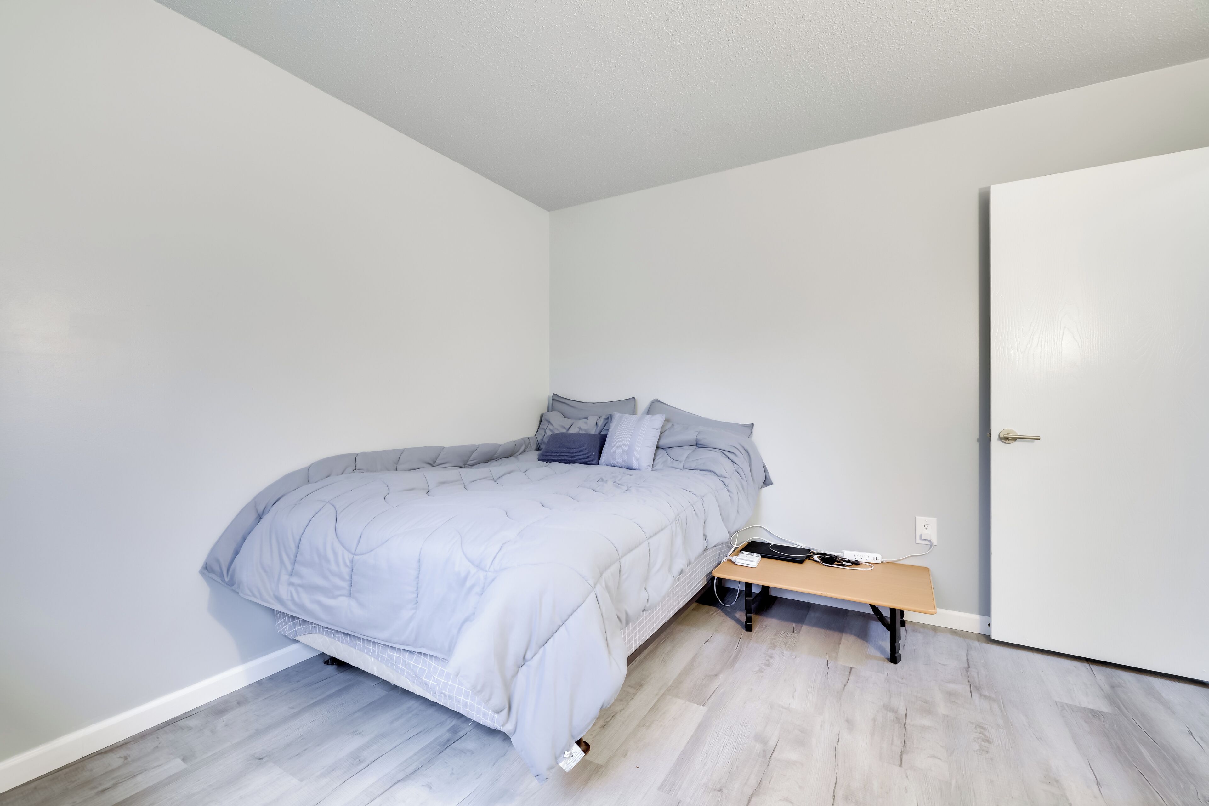 Een slaapkamer met een bed, een bankje en een deur.