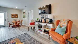 A living room with a dining area, a large flat-screen TV, and a patterned rug. - Brownsville Vacation Rental Near National Park! (Brownsville)