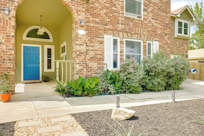 A brick house with a blue door, white shutters, and a small porch with a railing. - Hot Tub & Game Room: Spacious Live Oak Home! (San Antonio)
