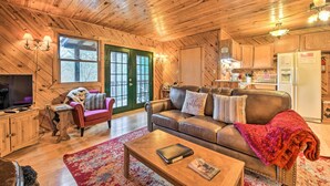 A cozy cabin interior with a living room, kitchen, and a large window. - Deck & Private Hot Tub! Maggie Valley Mtn Cabin (Maggie Valley)