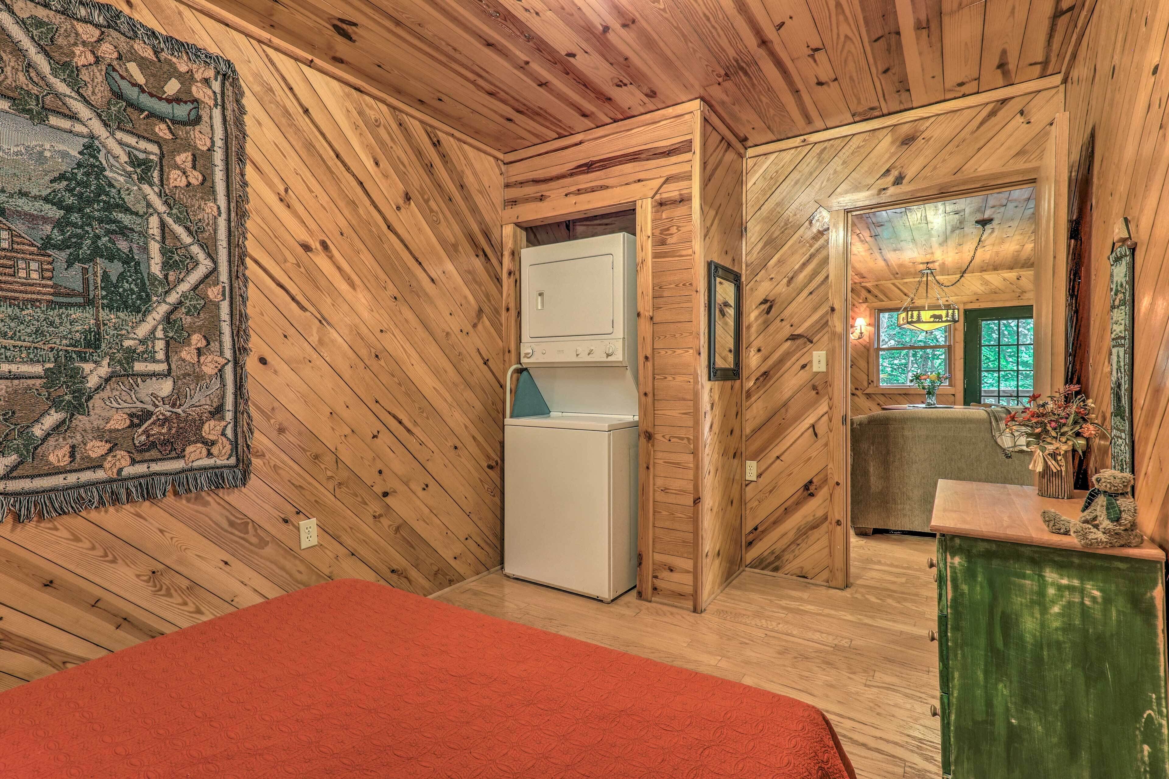 A cozy room with wooden walls, a bed, a refrigerator, and a small kitchenette.
