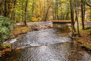 A forest stream with a concrete bridge, surrounded by trees and autumn foliage. - Hike & Ski! Blue Heron Brodheadsville Cottage (Brodheadsville)