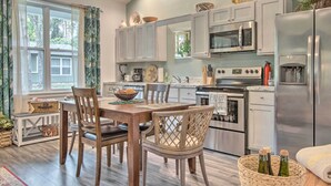 A modern kitchen with grey cabinets, stainless steel appliances, and a dining area with wooden chairs and a table. - Hike & Ski! Blue Heron Brodheadsville Cottage (Brodheadsville)