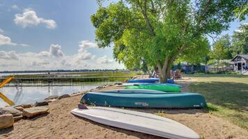A lakeside setting with kayaks and a paddleboard near a dock.