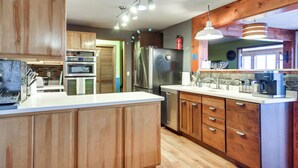 A modern kitchen with wooden cabinets, stainless steel appliances, and pendant lighting.
