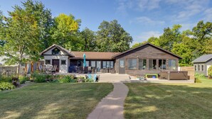 A two-story house with a covered patio, a front yard with a pathway, and a large backyard.