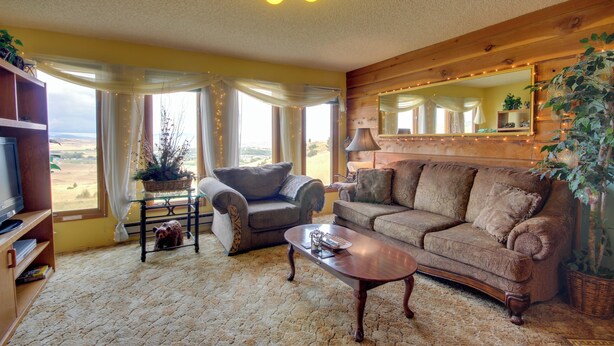 A cozy living room with a large window, a sofa, a coffee table, and a television. - Yellowstone Country Retreat: Stunning Views! (Livingston)