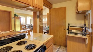 A compact kitchen with wooden cabinets, a stove, and a dish drying rack. - Yellowstone Country Retreat: Stunning Views! (Livingston)