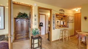 A cozy living room with a wooden cabinet, a small table with stools, and a wall decorated with various items. - Yellowstone Country Retreat: Stunning Views! (Livingston)