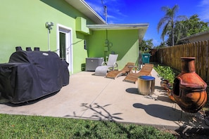 A patio with a grill, outdoor seating, and a large pot. - Tropical Naples Home Rental w/ Yard Near Beaches! (Naples)
