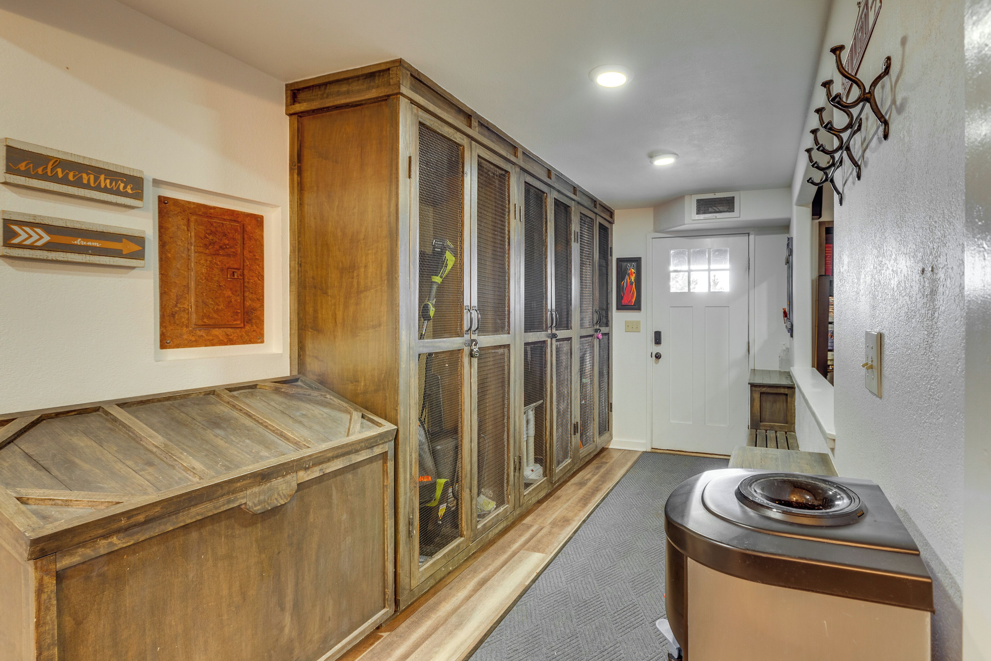 Un couloir avec une armoire en bois, un barbecue et un porte-manteau fixé au mur.