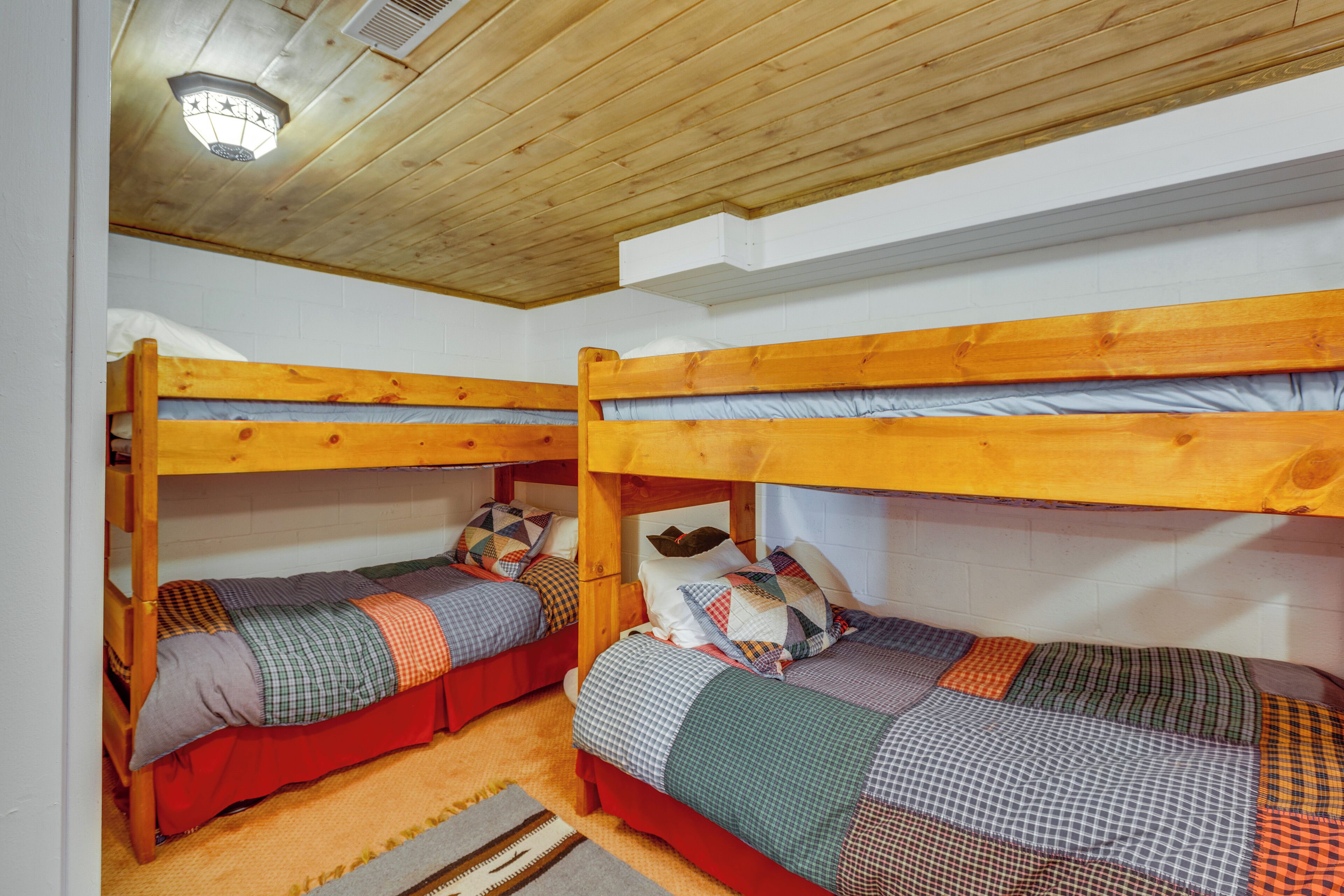 Une chambre de dortoir avec deux lits superposés, des têtes de lit en bois et un ventilateur de plafond.