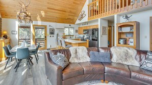A spacious living area with a brown leather sofa, a dining table with chairs, and a kitchen in the background. - Angel Fire Retreat w/ Hot Tub ~ 5 Mi to Skiing (Angel Fire)