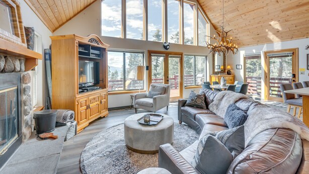 A spacious living room with a fireplace, large windows, and a high ceiling. - Angel Fire Retreat w/ Hot Tub ~ 5 Mi to Skiing (Angel Fire)