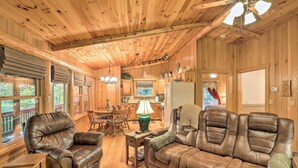 A wooden cabin interior with a living room, dining area, and kitchen. - Fletcher Cabin: Wraparound Deck & Pond Access (Fletcher)