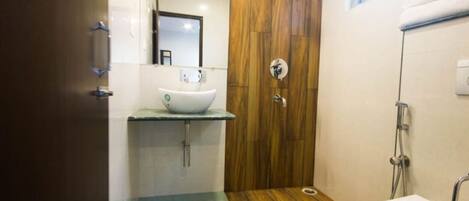 A bathroom with a wooden vanity, a white sink, and a shower.