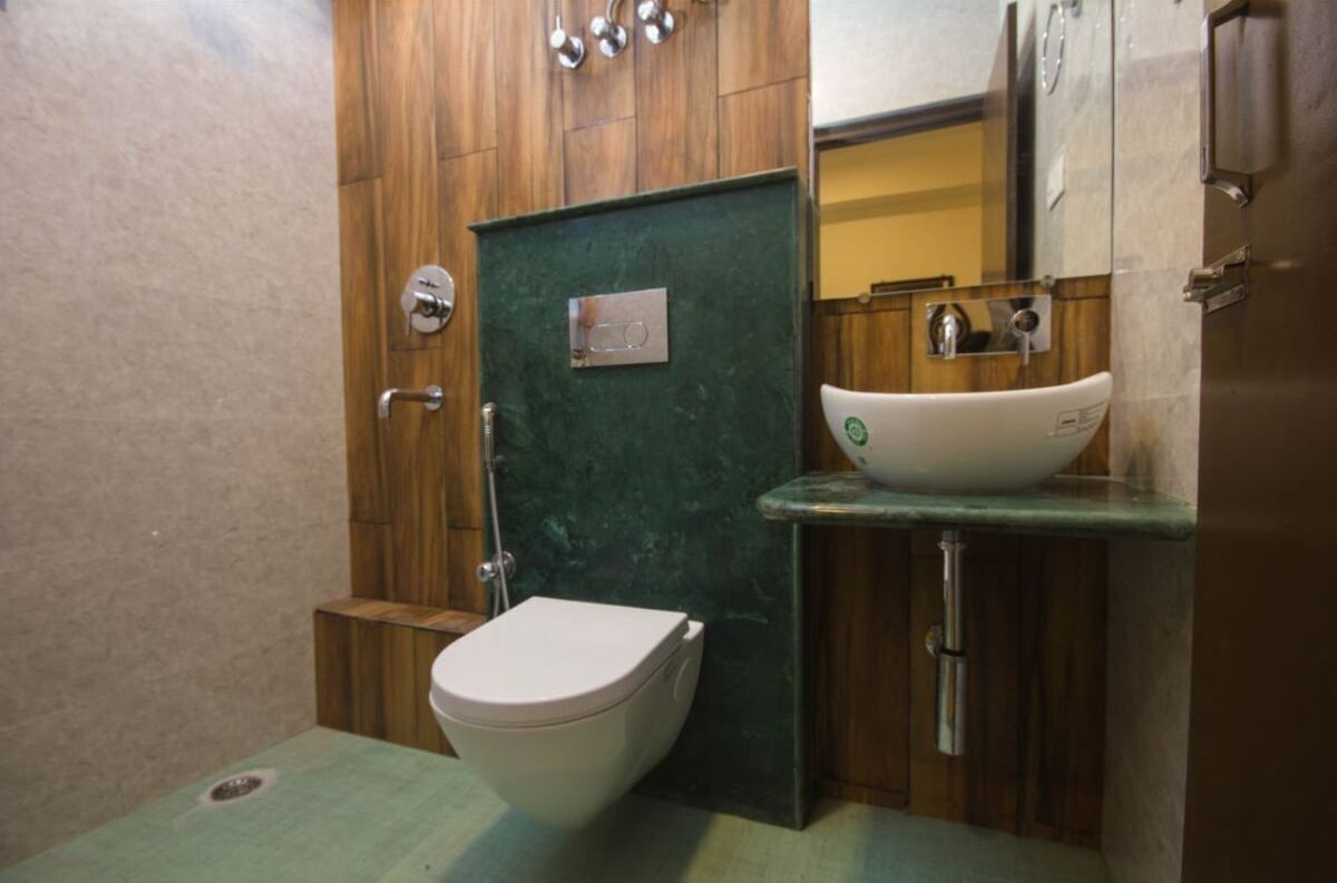Une petite salle de bain avec un meuble-lavabo en bois, des toilettes blanches et un lavabo vert.