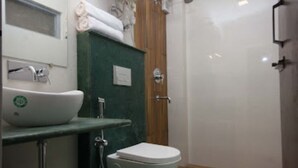 A bathroom with a white toilet, a sink with a green countertop, and a wooden door. - Bumble Bee (Gangtok)
