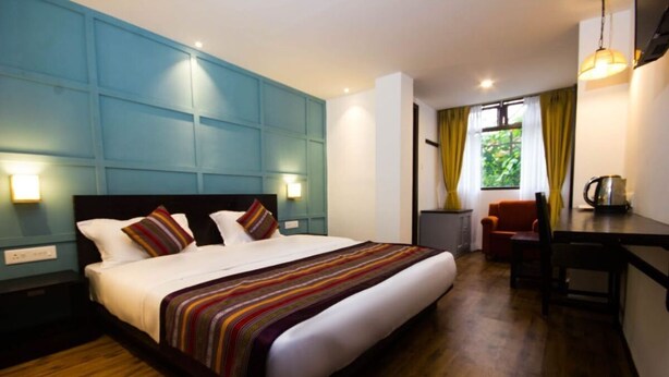 A hotel room with a large bed, a desk, and a chair. - Bumble Bee (Gangtok)