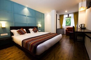 A hotel room with a large bed, a desk, and a chair.