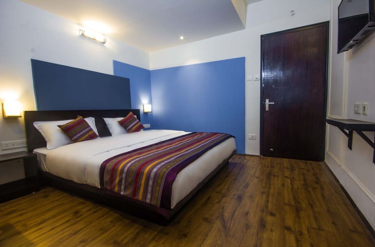Une chambre à coucher avec un lit, un plancher en bois et une porte.