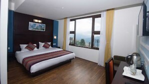 A hotel room with a large bed, a dining table, and a view of the mountains. - Bumble Bee (Gangtok)