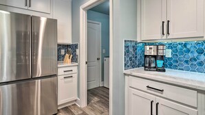 A modern kitchen with white cabinets, a stainless steel refrigerator, and a coffee maker on the counter. - 15 Mi to Beach: Home w/ Pool in Cape Coral (Cape Coral)