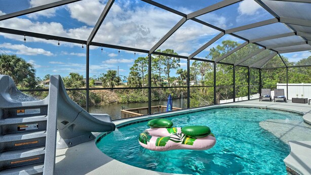 A covered swimming pool with a slide, surrounded by trees and a clear sky. - 15 Mi to Beach: Home w/ Pool in Cape Coral (Cape Coral)