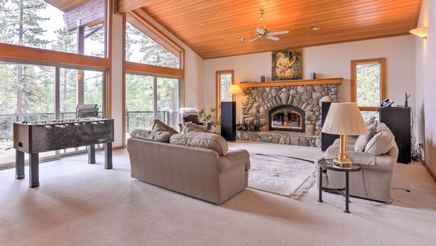 A spacious living room with a fireplace, a sofa, a coffee table, and a foosball table.