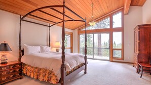 A four-poster bed with a wooden canopy, a nightstand with a lamp, and a dresser.